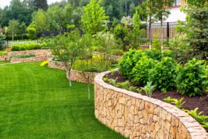 Jardins aménagés en terrasses avec murets en pierre et arbustes variés.
