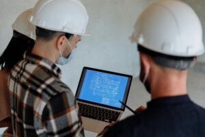 Plans architecturaux posés sur un bureau avec des outils de mesure et un ordinateur portable.