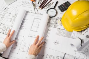 Consultation de plans architecturaux avec des outils de mesure pour évaluer les risques sur un chantier.